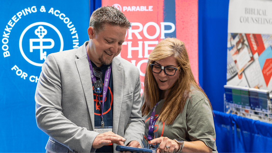 Two Parable representatives smiling and looking at a tablet in a conference booth.
