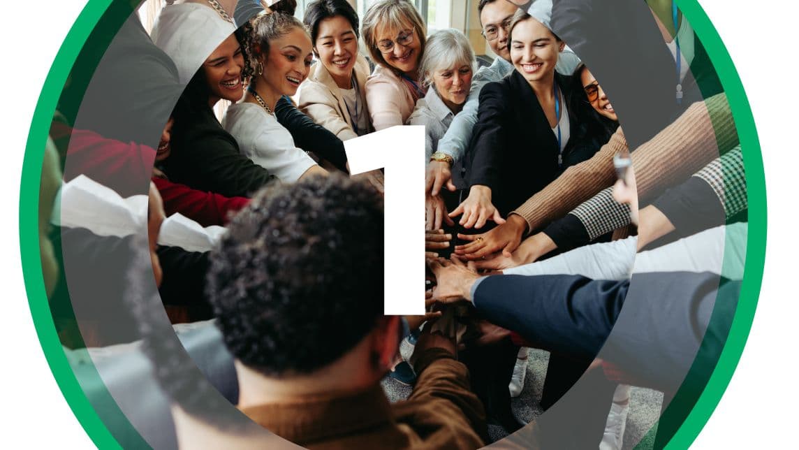 Team members standing in a circle with hands joined in the center, symbolizing unity and collaboration.
