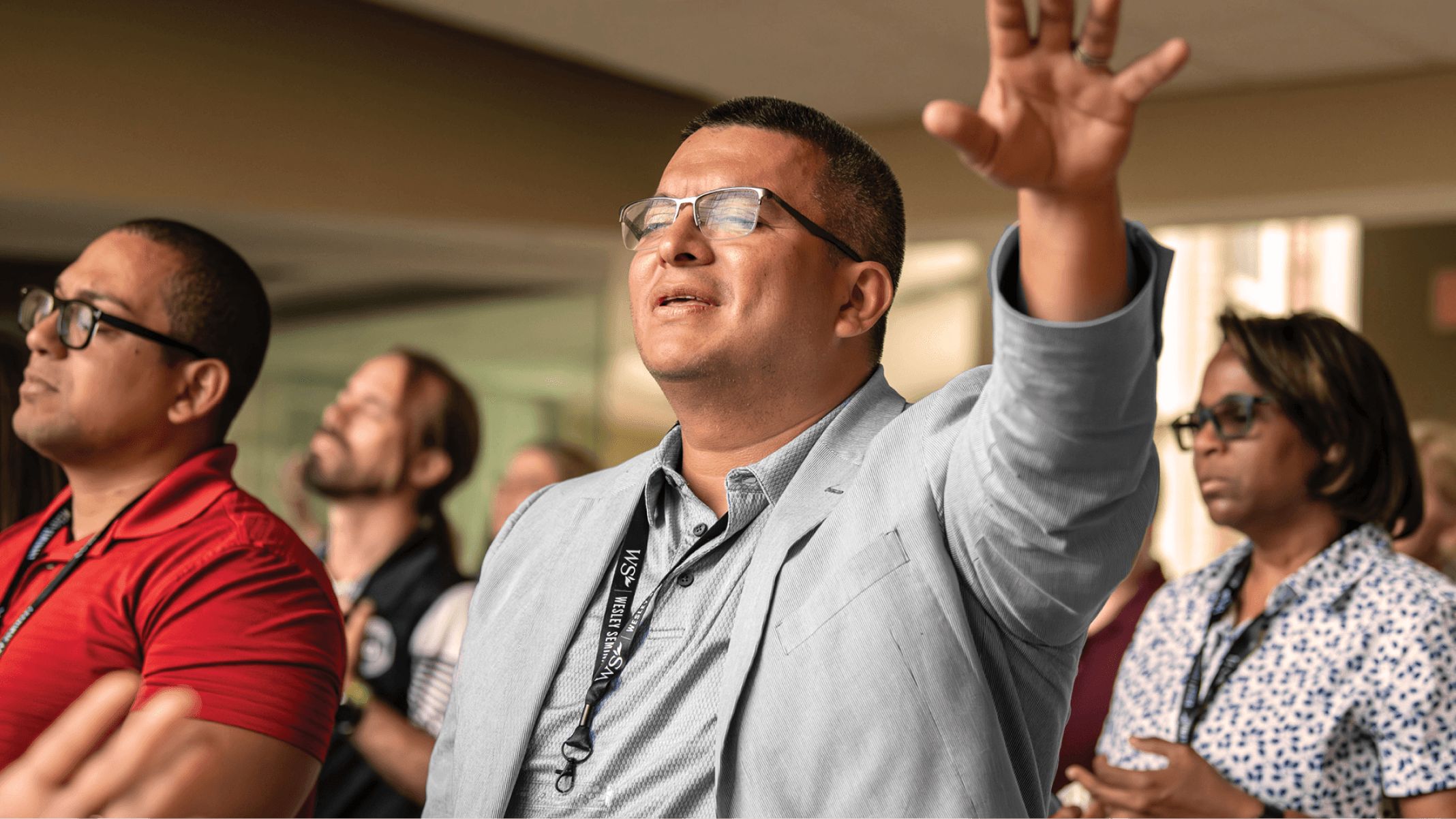 Student raising hand during a seminar or worship setting.