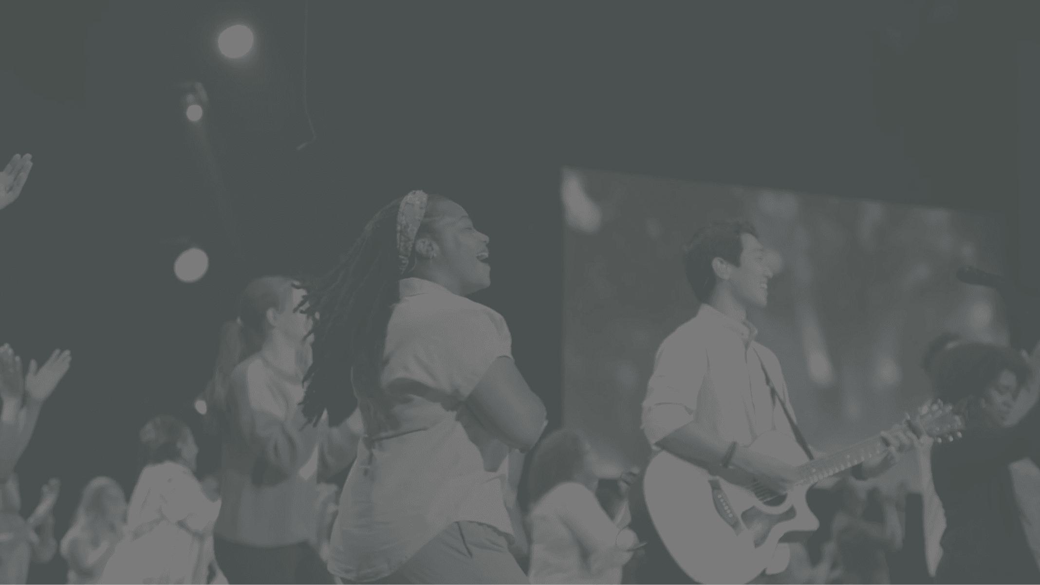 Group of people worshiping in a church setting, raising hands in praise.