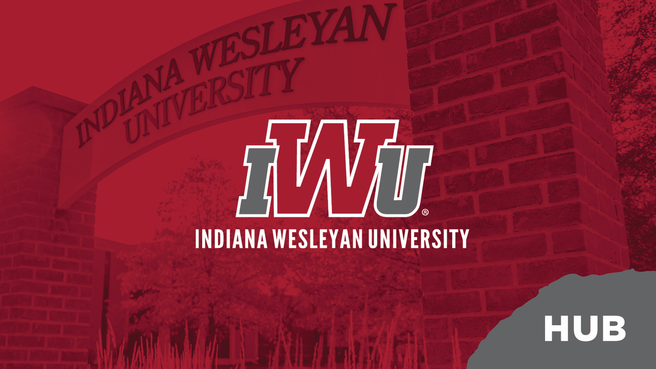 Indiana Wesleyan University entrance sign with IWU logo and text ‘Indiana Wesleyan University’ over a red-tinted background labeled ‘Hub.’